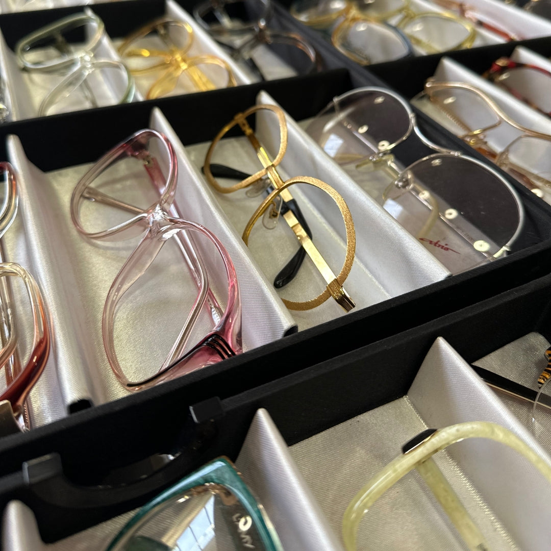 A selection of vintage eyewear frames in different materials, including acetate, Optyl, Perspex, metal, and rolled gold, showcasing the variety of textures, colours, and designs found in classic glasses.